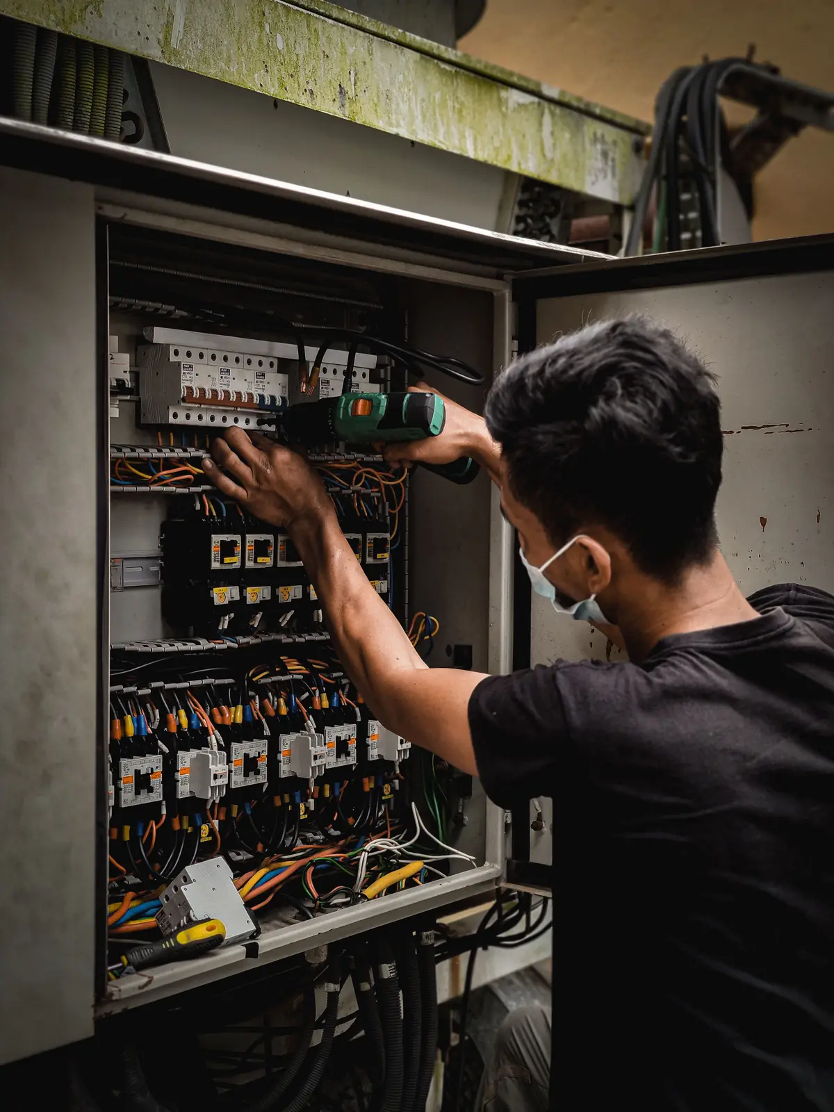 An electrician working inside a large distribution board, for commercial electrical in Winnipeg