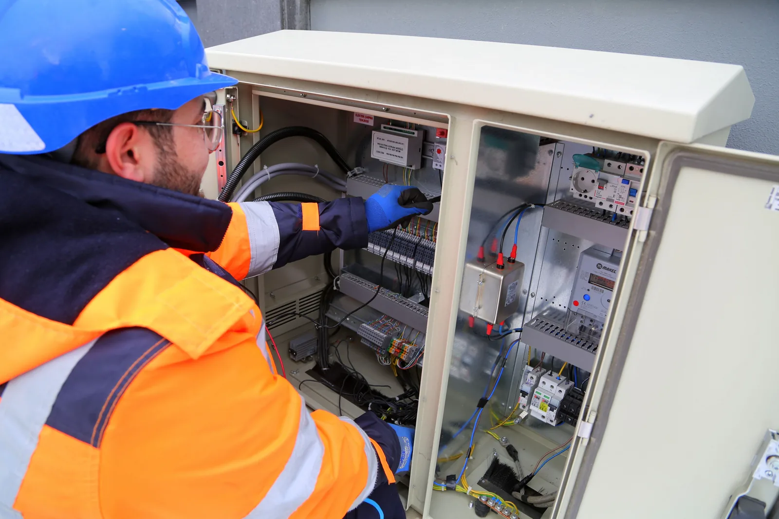 An electrician working in an outdoor service cabinet, for grounding and bonding in Winnipeg